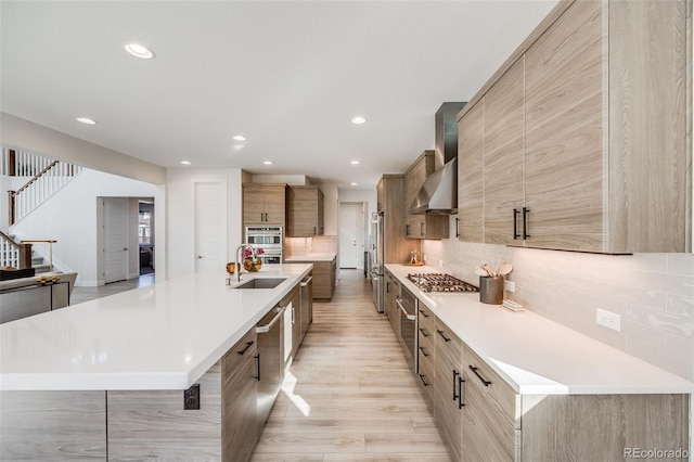 kitchen with stainless steel appliances, light countertops, wall chimney exhaust hood, and modern cabinets