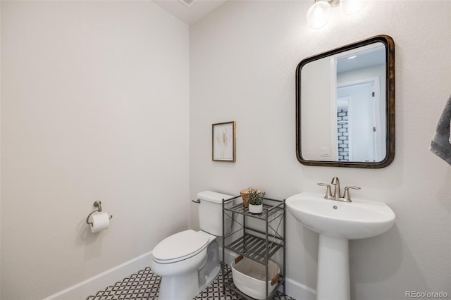 half bath with baseboards and toilet