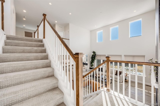 staircase featuring a high ceiling, wood finished floors, and recessed lighting