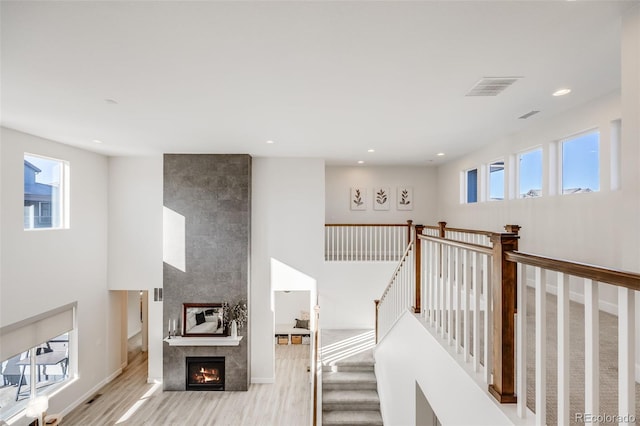 interior space with a large fireplace, a wealth of natural light, wood finished floors, and visible vents