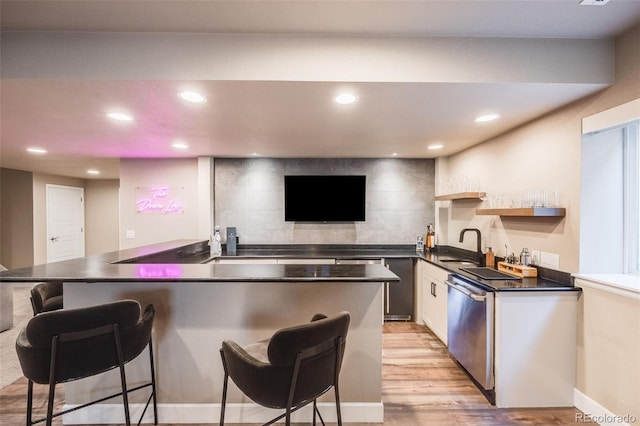 kitchen featuring dark countertops, dishwasher, backsplash, and a breakfast bar area