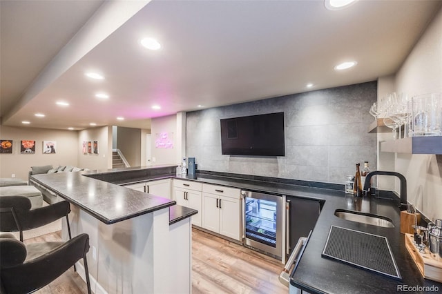 kitchen with beverage cooler, decorative backsplash, dark countertops, open floor plan, and a sink