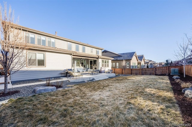 back of property with fence, a lawn, and a patio