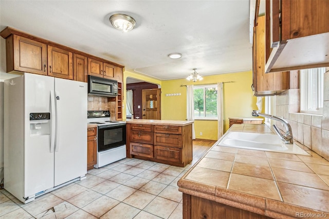 1457 S Franklin St, Denver, CO 80210 - kitchen featuring white refrigerator with ice dispenser, electric range, black microwave, brown cabinetry, and a peninsula