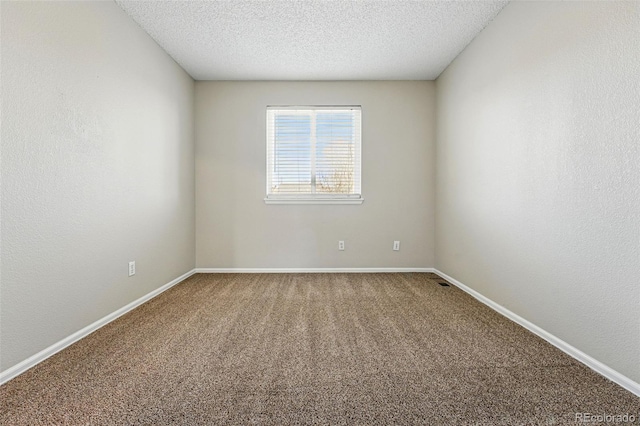 empty room featuring carpet, a textured ceiling, and baseboards