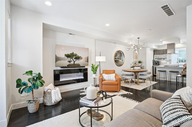 living area with a glass covered fireplace, visible vents, recessed lighting, and wood finished floors