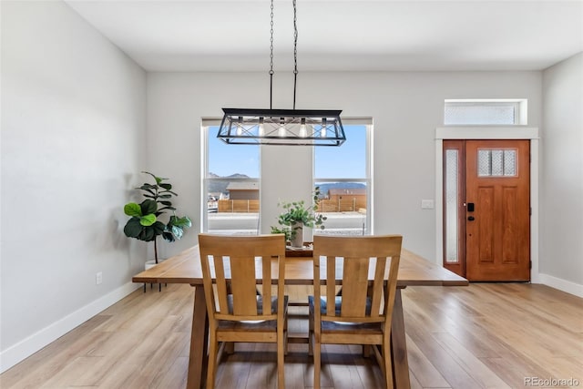 dining room with an inviting chandelier, baseboards, and light wood-type flooring