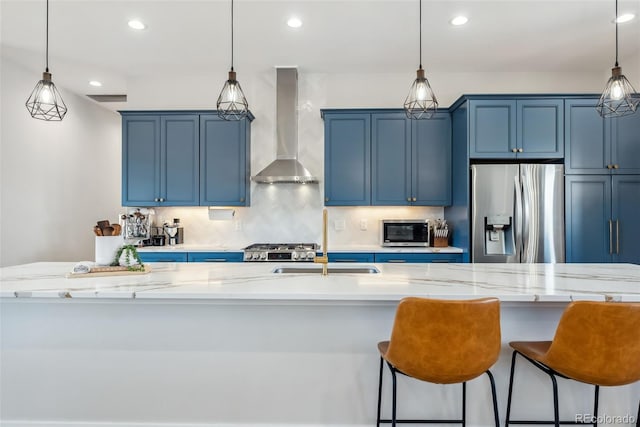 kitchen featuring wall chimney exhaust hood, stainless steel appliances, a sink, backsplash, and blue cabinetry