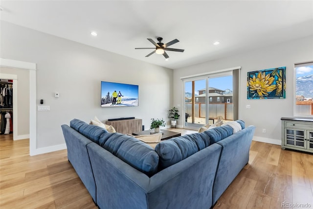 living area featuring baseboards, a ceiling fan, and light wood-style floors