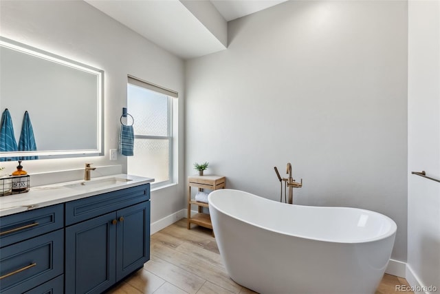 full bath featuring baseboards, a soaking tub, and vanity