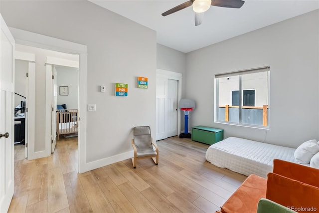 living area with baseboards, a ceiling fan, and light wood-style flooring