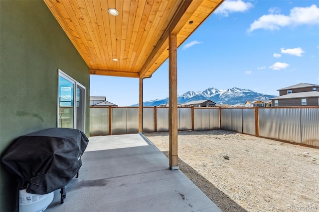 view of patio / terrace featuring grilling area, a mountain view, and a fenced backyard