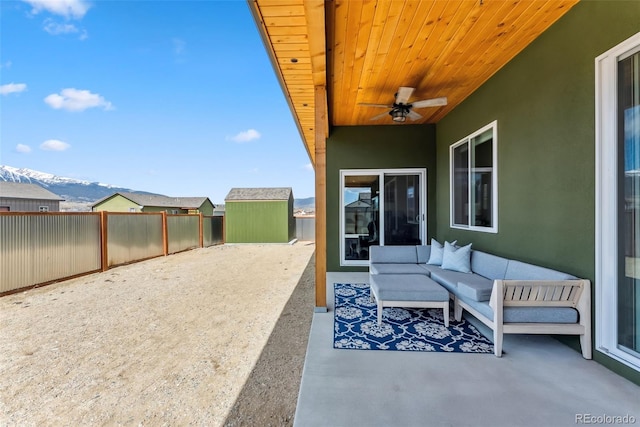 view of patio featuring a mountain view, an outdoor living space, a ceiling fan, and a fenced backyard