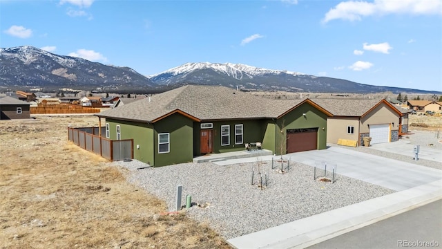 ranch-style house with an attached garage, driveway, a mountain view, and stucco siding