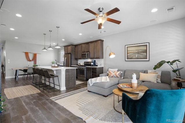 living room featuring ceiling fan and dark hardwood / wood-style flooring