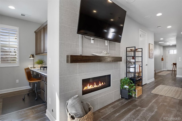 living room with dark wood-type flooring and a tile fireplace