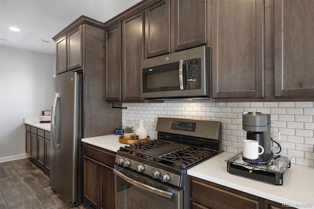 kitchen featuring dark brown cabinetry, dark wood-type flooring, tasteful backsplash, and appliances with stainless steel finishes