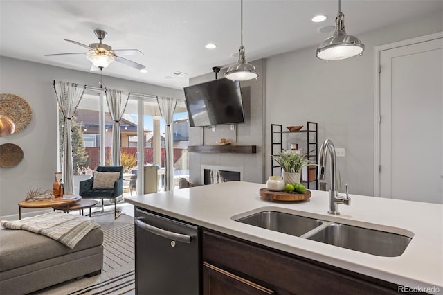 kitchen with sink, dark brown cabinets, stainless steel dishwasher, a large fireplace, and pendant lighting