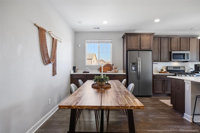 kitchen with decorative backsplash, dark brown cabinets, dark wood-type flooring, and appliances with stainless steel finishes