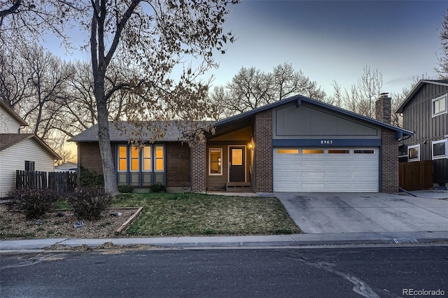 view of front of property with brick siding, an attached garage, driveway, and fence