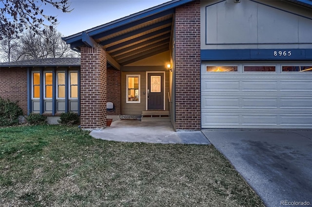 view of front of home featuring a garage, driveway, brick siding, and a front yard