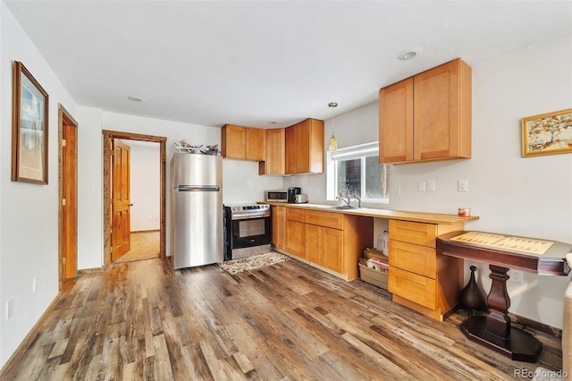 kitchen featuring hanging light fixtures, sink, stainless steel appliances, and hardwood / wood-style floors