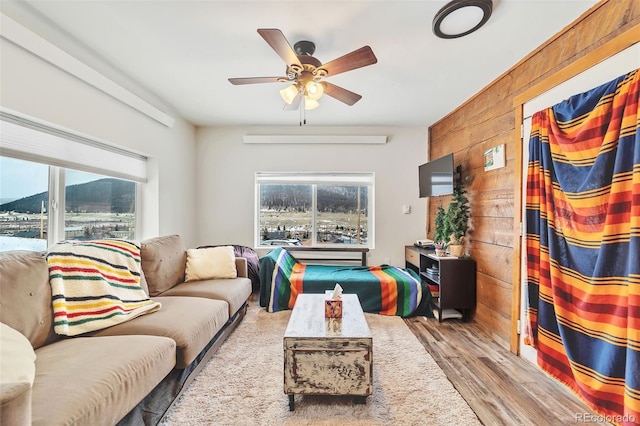 living room with ceiling fan, plenty of natural light, wooden walls, and light hardwood / wood-style flooring