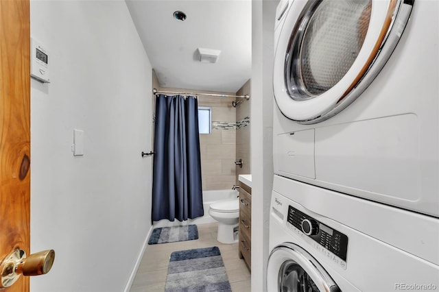 full bathroom featuring shower / tub combo with curtain, vanity, toilet, and stacked washer / dryer