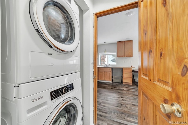 clothes washing area with dark hardwood / wood-style flooring, sink, and stacked washer and clothes dryer