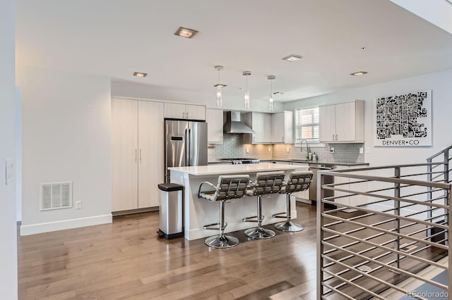 1840 Irving St, Denver, CO 80204 - kitchen with stainless steel appliances, wall chimney exhaust hood, a kitchen bar, light wood finished floors, and recessed lighting