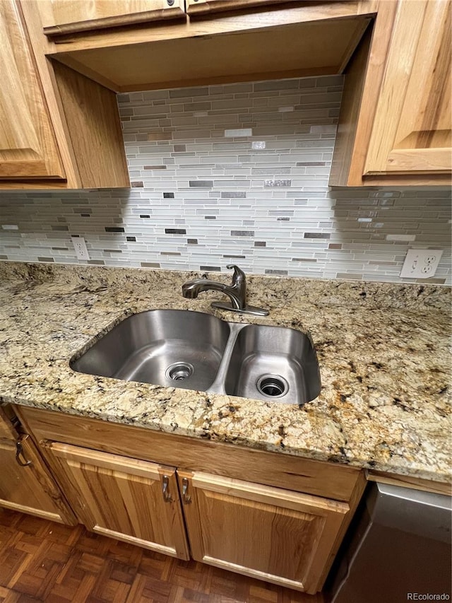 room details featuring decorative backsplash, dark parquet flooring, light stone countertops, and sink