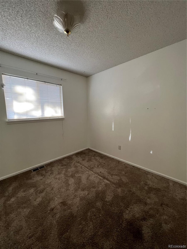 carpeted empty room with a textured ceiling