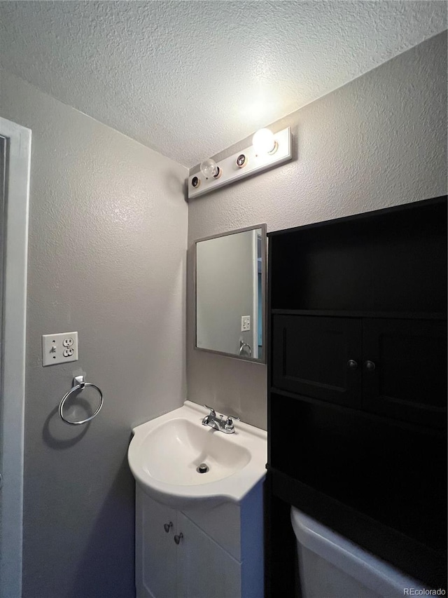 bathroom featuring vanity, a textured ceiling, and toilet