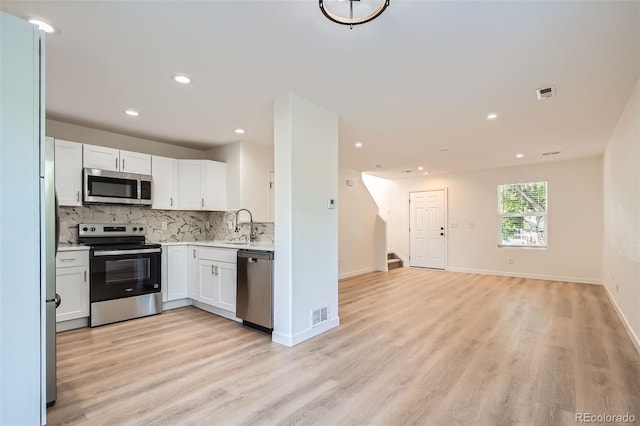 1272 Bluebird St, Brighton, CO 80601 - kitchen featuring stainless steel appliances, open floor plan, light wood finished floors, decorative backsplash, and light countertops
