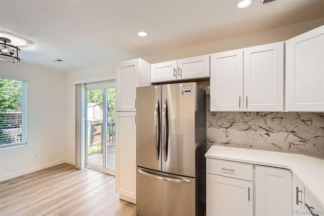 1272 Bluebird St, Brighton, CO 80601 - kitchen featuring freestanding refrigerator, white cabinetry, light wood-style flooring, light countertops, and decorative backsplash