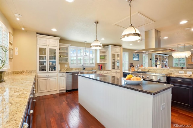 kitchen with island exhaust hood, dark stone counters, stainless steel appliances, dark wood-type flooring, and white cabinets