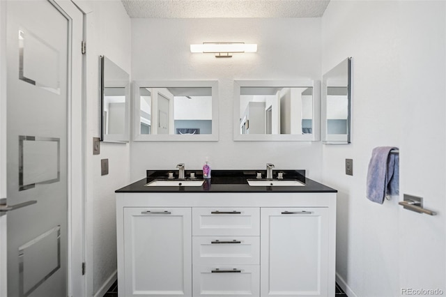 3904 Breaking Dawn St, Colorado Springs, CO 80925 - bathroom featuring double vanity, a textured ceiling, and baseboards