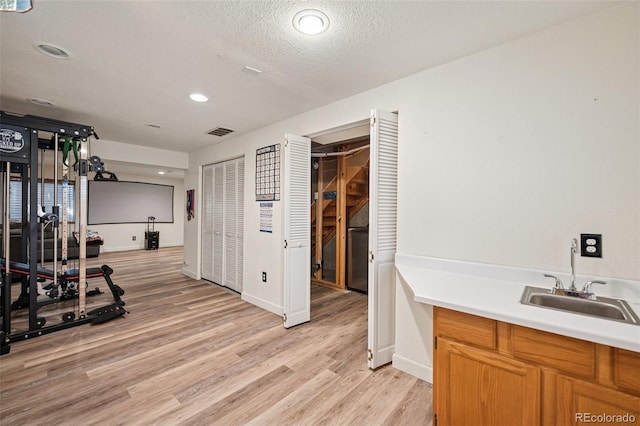 3904 Breaking Dawn St, Colorado Springs, CO 80925 - workout room with a sink, light wood finished floors, a textured ceiling, recessed lighting, and baseboards
