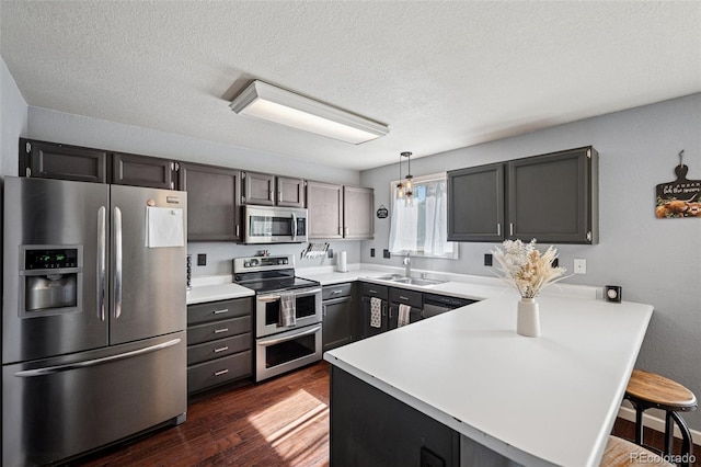 3904 Breaking Dawn St, Colorado Springs, CO 80925 - kitchen with appliances with stainless steel finishes, a peninsula, dark wood-type flooring, light countertops, and a textured ceiling