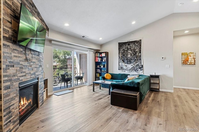 living room with a fireplace, light hardwood / wood-style floors, and vaulted ceiling