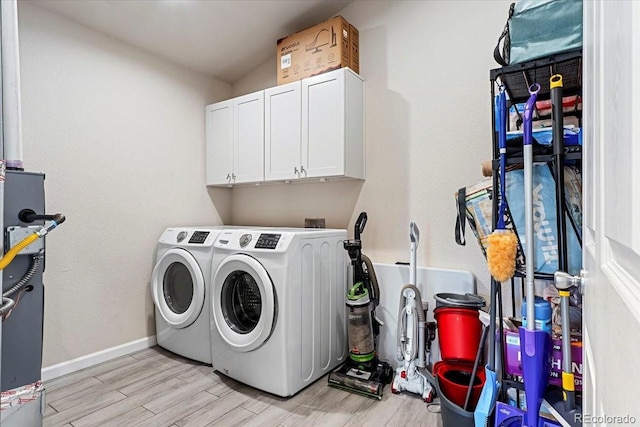 washroom featuring washing machine and dryer, light hardwood / wood-style flooring, and cabinets