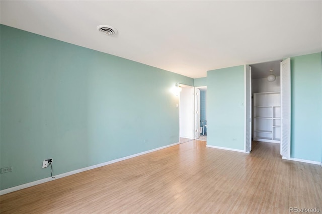unfurnished room featuring baseboards, wood finished floors, and visible vents