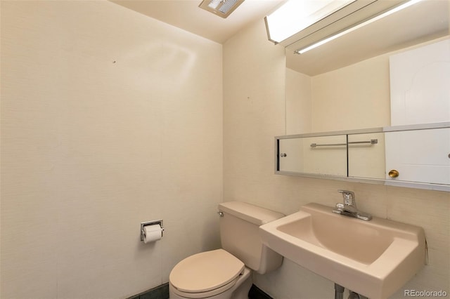 half bathroom with visible vents, a sink, and toilet