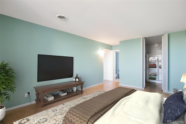 bedroom featuring baseboards, wood finished floors, and visible vents