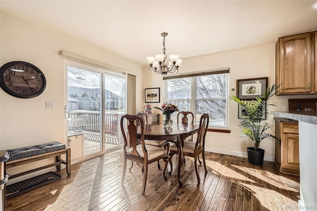 dining space featuring dark wood-style floors, a chandelier, and baseboards