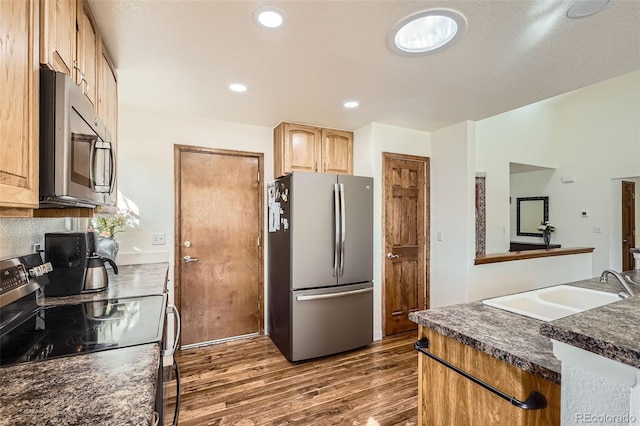 kitchen featuring recessed lighting, a sink, appliances with stainless steel finishes, dark wood-style floors, and dark countertops