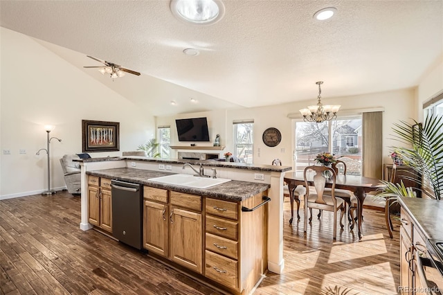 kitchen featuring dark wood finished floors, dishwasher, lofted ceiling, dark countertops, and a sink