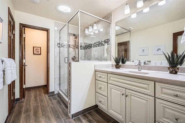 full bath featuring baseboards, a shower stall, vanity, and wood tiled floor