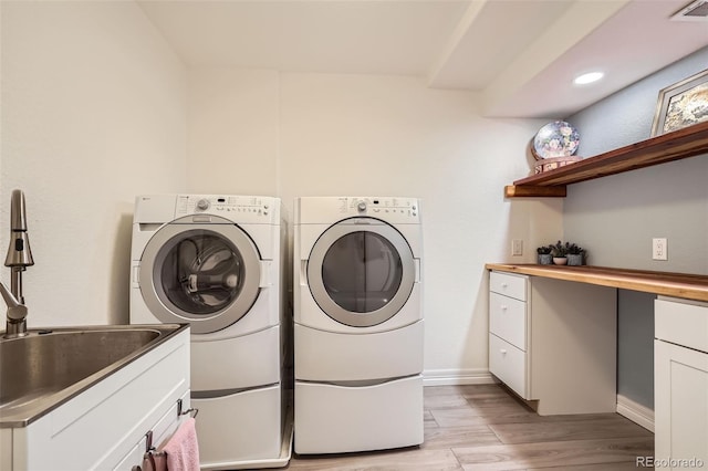 washroom with washing machine and clothes dryer, cabinet space, visible vents, light wood-style flooring, and a sink