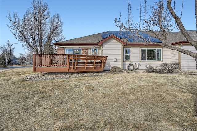 back of house featuring solar panels, a lawn, and a wooden deck